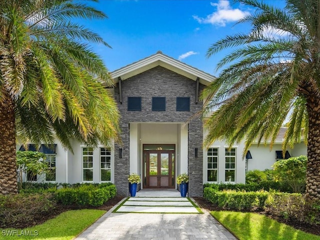 view of exterior entry featuring stone siding, french doors, and stucco siding