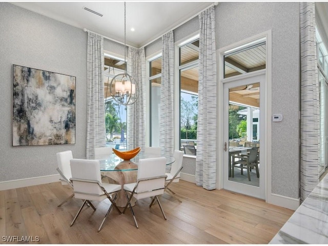 dining space with crown molding, visible vents, a chandelier, light wood-type flooring, and baseboards