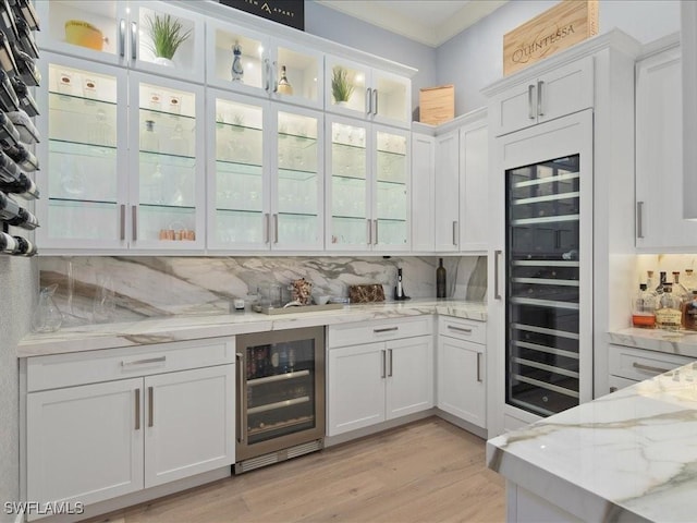 bar featuring beverage cooler, a dry bar, light wood finished floors, and decorative backsplash