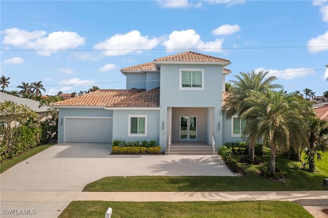 mediterranean / spanish-style home with a garage, a front yard, and french doors