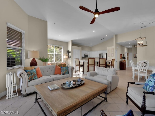 living room featuring ceiling fan with notable chandelier, light tile patterned floors, and high vaulted ceiling