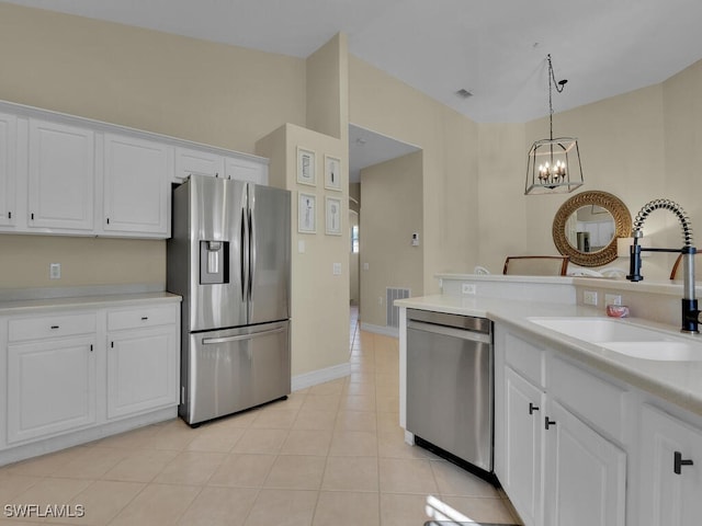 kitchen featuring light tile patterned flooring, white cabinetry, appliances with stainless steel finishes, a notable chandelier, and sink