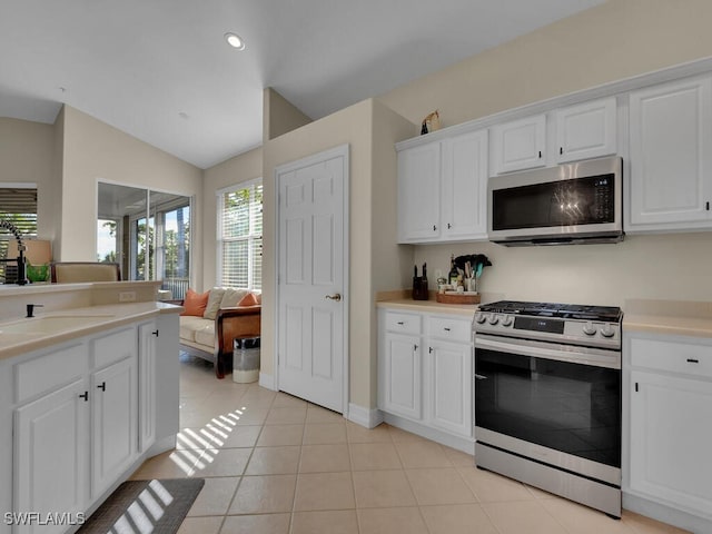 kitchen with white cabinetry, appliances with stainless steel finishes, lofted ceiling, and light tile patterned floors