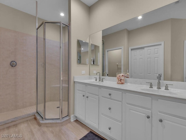 bathroom with walk in shower, vanity, and hardwood / wood-style flooring