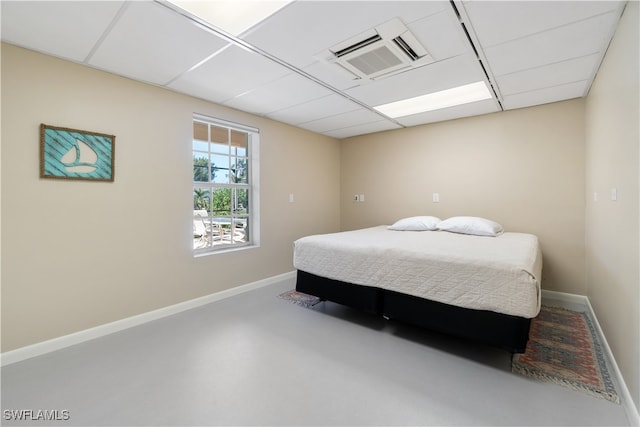 bedroom with concrete flooring and a paneled ceiling