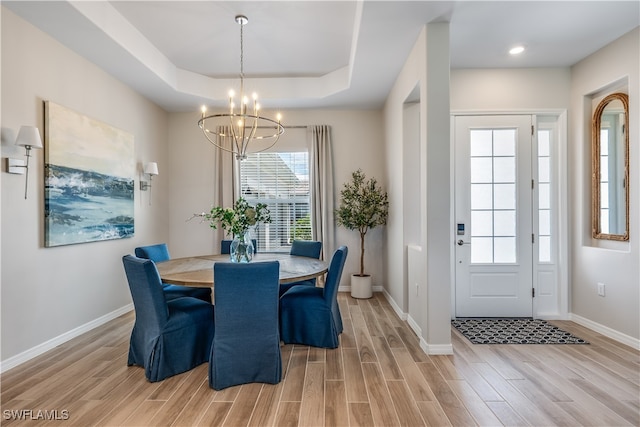 dining room with light hardwood / wood-style floors, a chandelier, and a tray ceiling