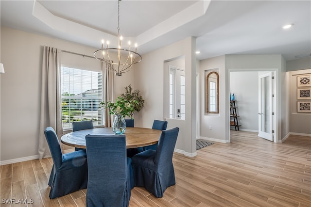 dining room with a chandelier, french doors, a raised ceiling, and light hardwood / wood-style flooring