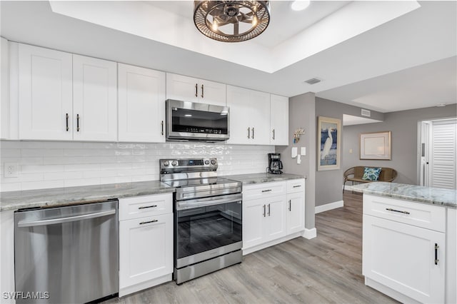 kitchen featuring white cabinetry, appliances with stainless steel finishes, backsplash, and light hardwood / wood-style flooring