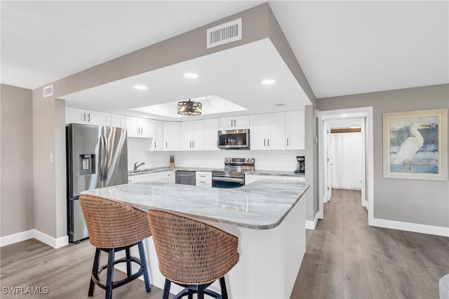 kitchen with white cabinetry, light hardwood / wood-style floors, light stone countertops, and stainless steel appliances