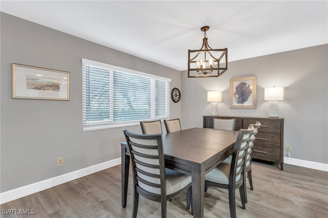 dining space with hardwood / wood-style floors and an inviting chandelier