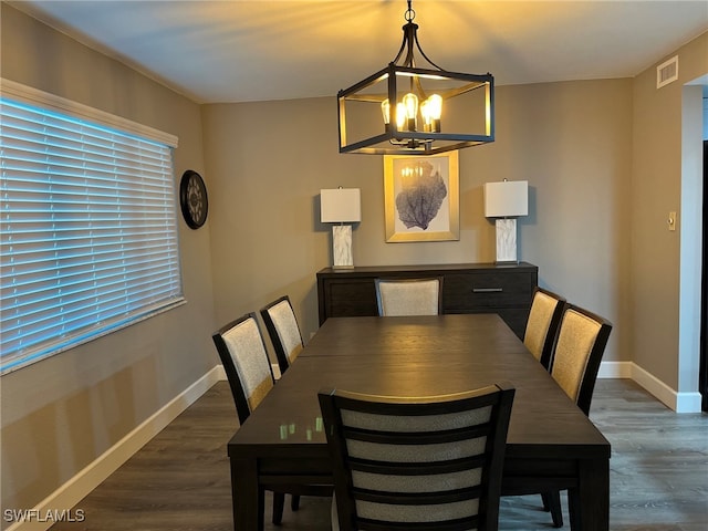 dining space with dark wood-type flooring and a chandelier