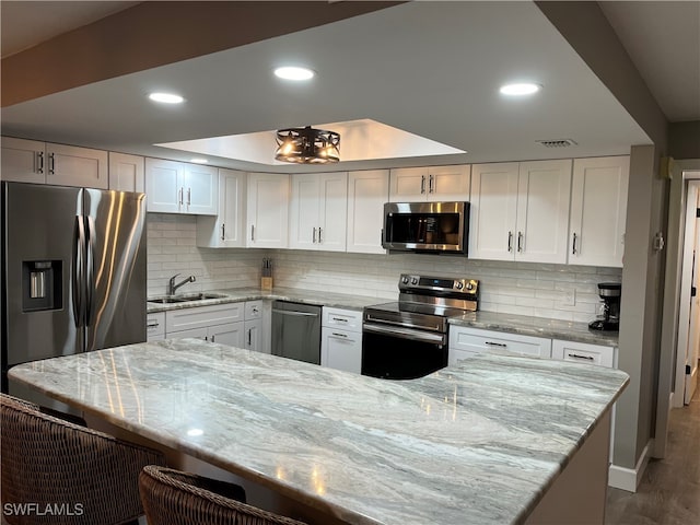 kitchen featuring stainless steel appliances, hardwood / wood-style floors, sink, backsplash, and white cabinetry