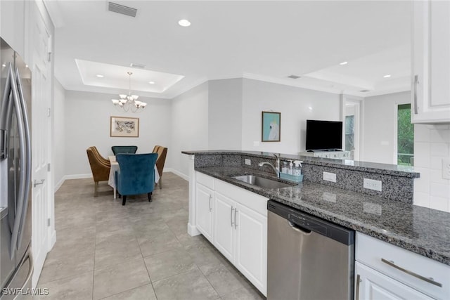 kitchen featuring stainless steel appliances, a tray ceiling, sink, dark stone countertops, and white cabinets