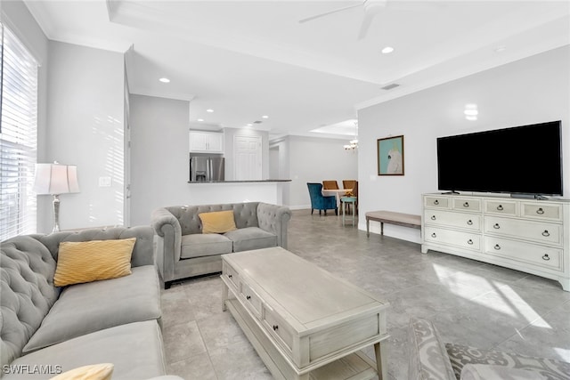 living room featuring a tray ceiling, ceiling fan, light tile patterned flooring, and ornamental molding