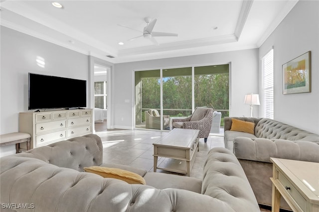 living room with ceiling fan, light tile patterned flooring, crown molding, and a tray ceiling