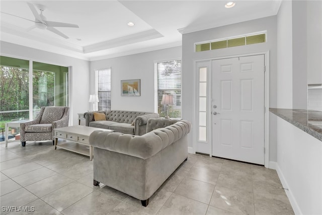 tiled living room featuring a raised ceiling, crown molding, and ceiling fan