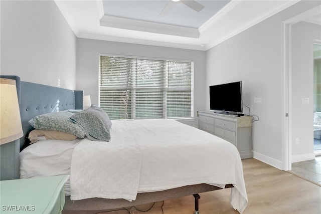 bedroom with light hardwood / wood-style floors, a raised ceiling, ceiling fan, and ornamental molding