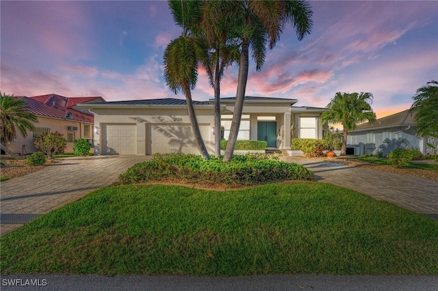 ranch-style house with a garage and a lawn