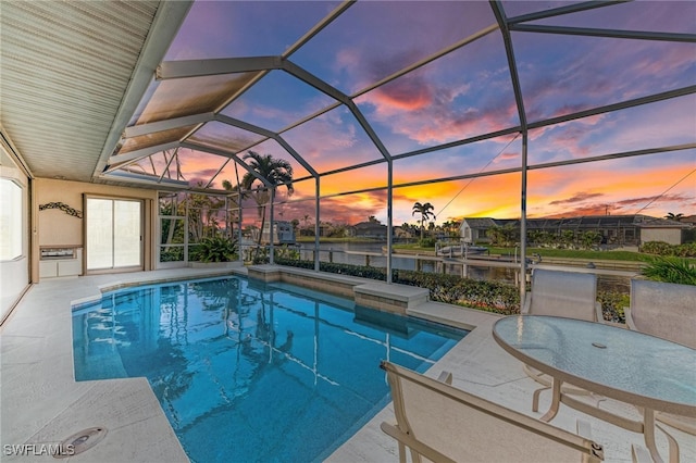 pool at dusk featuring glass enclosure and a patio area