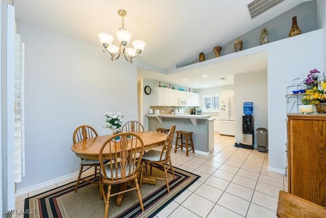 tiled dining space featuring vaulted ceiling, sink, and an inviting chandelier