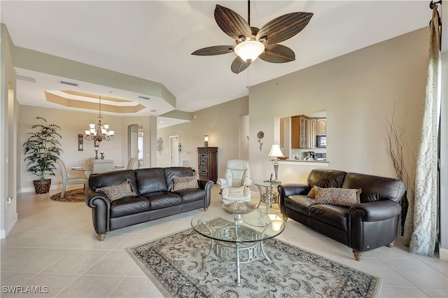 tiled living room with ceiling fan with notable chandelier and a raised ceiling