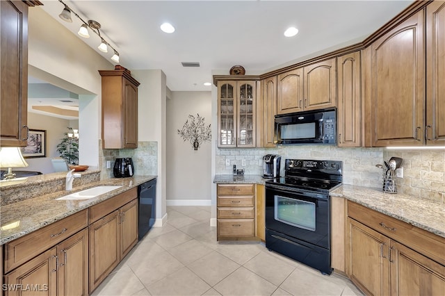 kitchen featuring backsplash, light stone counters, sink, and black appliances