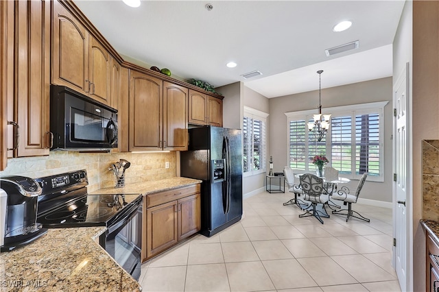 kitchen featuring decorative backsplash, light stone countertops, black appliances, a chandelier, and hanging light fixtures