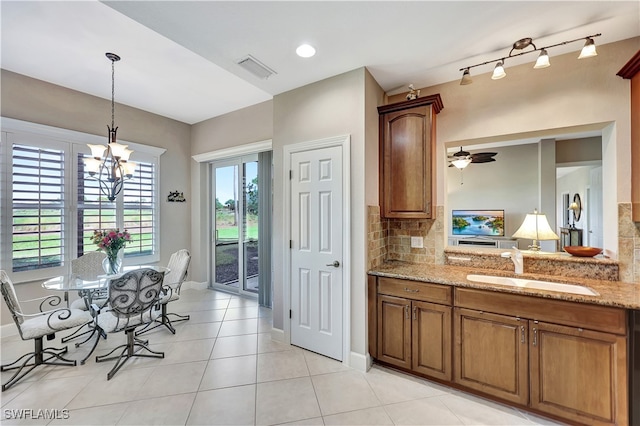 kitchen with light stone countertops, backsplash, rail lighting, sink, and light tile patterned flooring