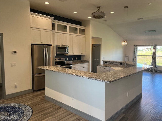 kitchen featuring vaulted ceiling, hanging light fixtures, a kitchen island, white cabinetry, and appliances with stainless steel finishes