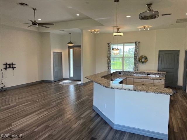 kitchen with white cabinets, decorative light fixtures, dark hardwood / wood-style floors, and stone countertops