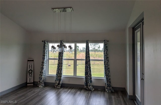 unfurnished room featuring dark wood-type flooring, vaulted ceiling, and an inviting chandelier