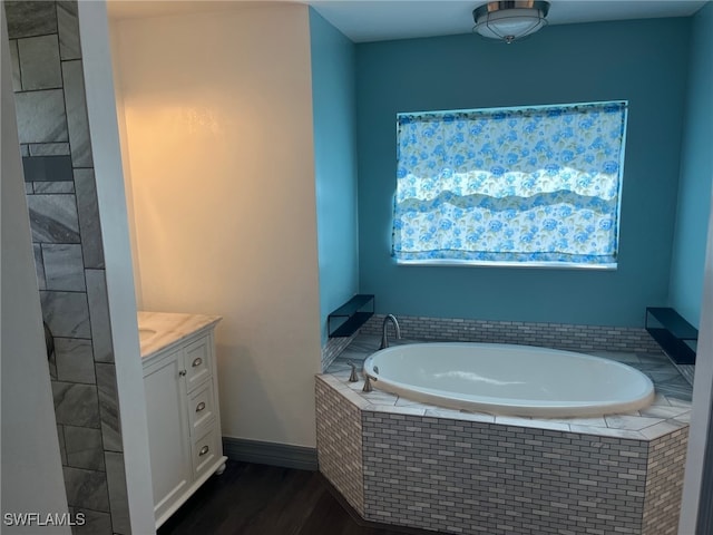 bathroom with hardwood / wood-style flooring, vanity, and a relaxing tiled tub