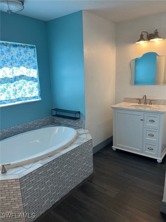 bathroom featuring tiled bath, hardwood / wood-style floors, and vanity