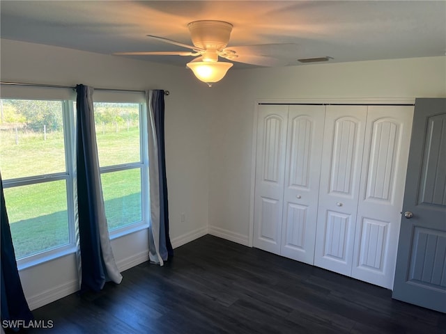 unfurnished bedroom with dark wood-type flooring, ceiling fan, and a closet