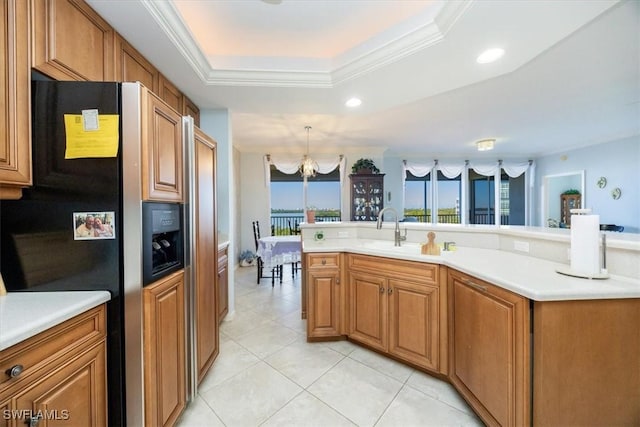 kitchen with a raised ceiling, sink, refrigerator with ice dispenser, decorative light fixtures, and an inviting chandelier