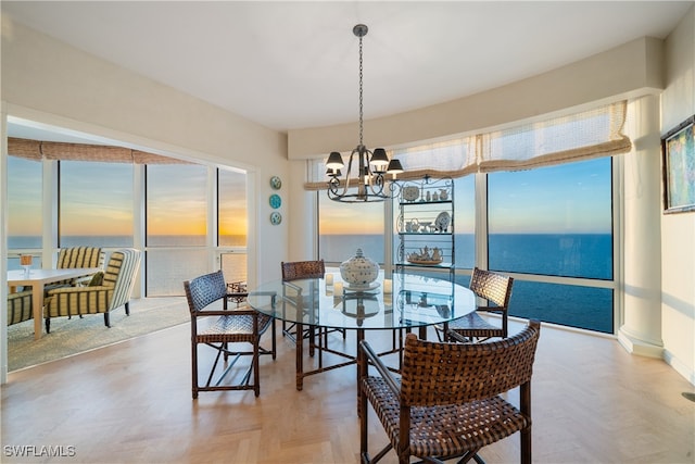 dining area with a chandelier, a water view, and parquet floors