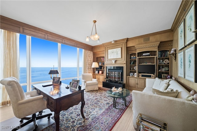 living room with light wood-type flooring, a water view, and wooden walls