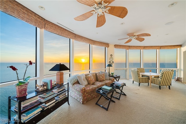 living room with carpet flooring, a wall of windows, a water view, and ceiling fan