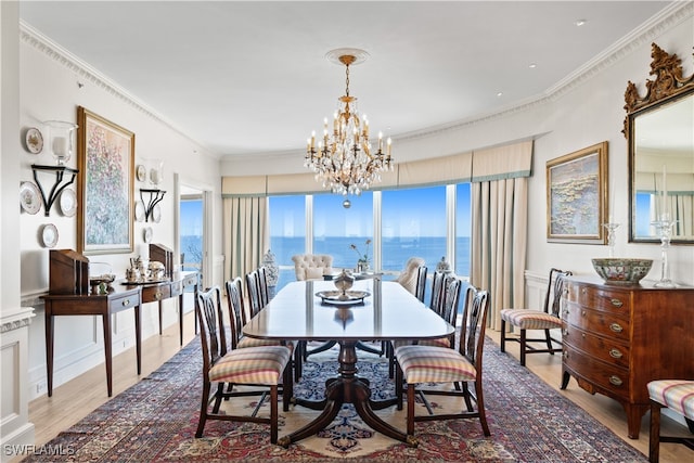 dining area with a chandelier, crown molding, a water view, and light hardwood / wood-style floors