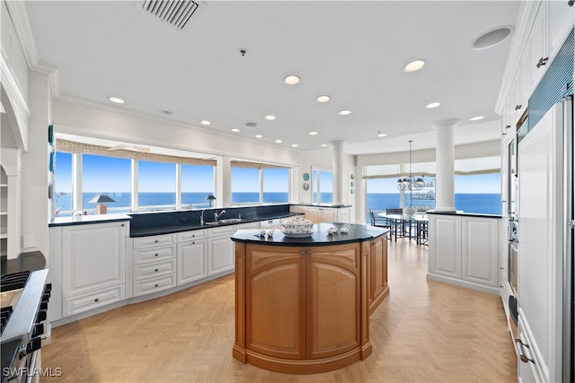 kitchen with a center island, white cabinetry, plenty of natural light, and a water view