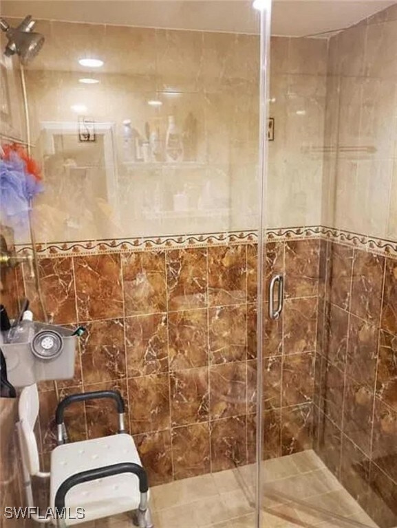 bathroom with walk in shower, tile walls, and tile patterned floors