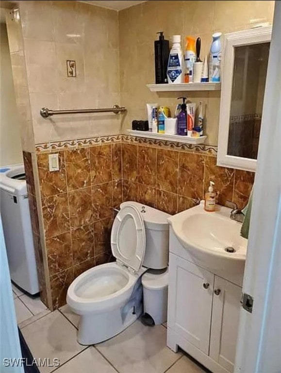 bathroom featuring tile walls, vanity, washer / clothes dryer, toilet, and tile patterned floors