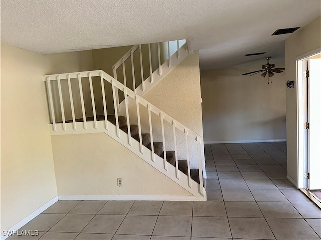 staircase featuring tile patterned floors, ceiling fan, and a textured ceiling