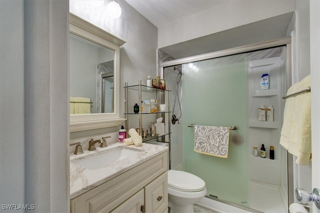 bathroom with vanity, toilet, and a shower with door