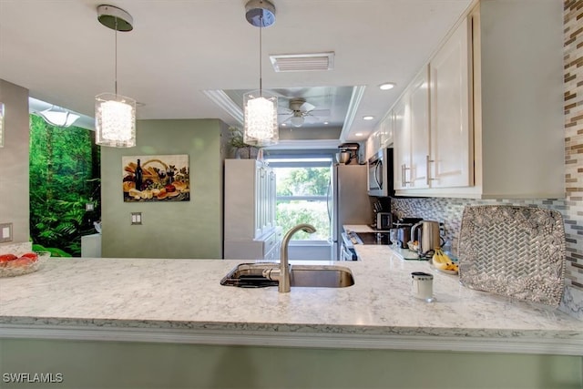 kitchen with stainless steel appliances, sink, light stone countertops, ceiling fan, and decorative light fixtures