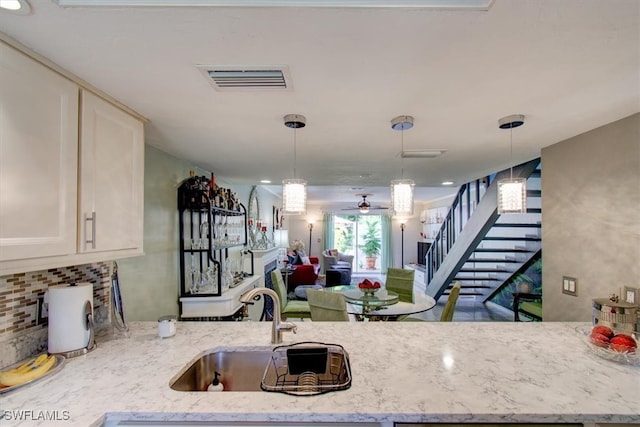 kitchen with decorative light fixtures, sink, and light stone counters