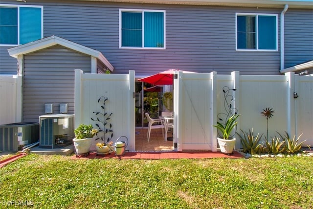 back of house with central air condition unit and a yard