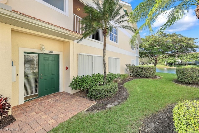 property entrance featuring a balcony and a yard