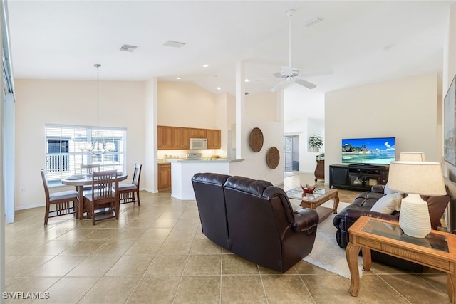 living room with high vaulted ceiling, light tile patterned floors, and ceiling fan with notable chandelier