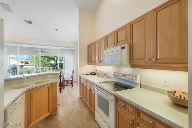 kitchen featuring decorative light fixtures, light tile patterned floors, sink, white appliances, and a high ceiling